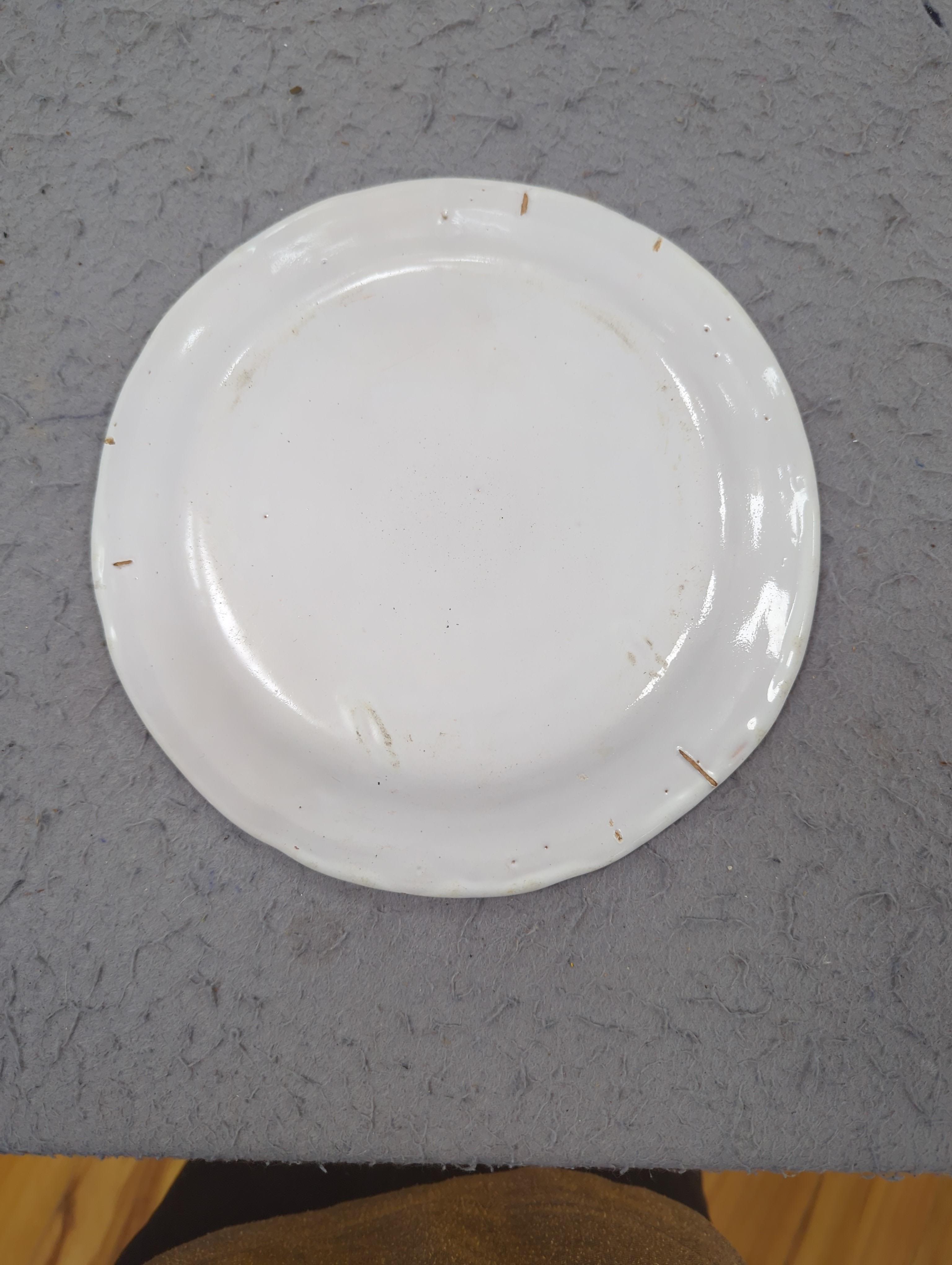 An 18th century Delft plate and three 19th century faience plates, largest 26cm diameter (4)